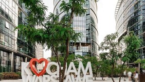 A modern building with large glass windows and a sign that reads "KOMAM WARSZAWIE" with a heart symbol.