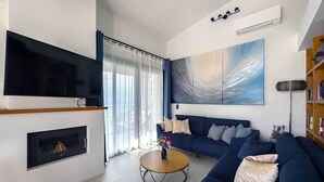 Un salon moderne avec une grande télévision, une cheminée, un ensemble de canapés et un tableau accroché au mur.