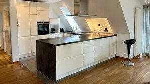 Una cocina moderna con una isla central, electrodomésticos integrados y un tragaluz.
