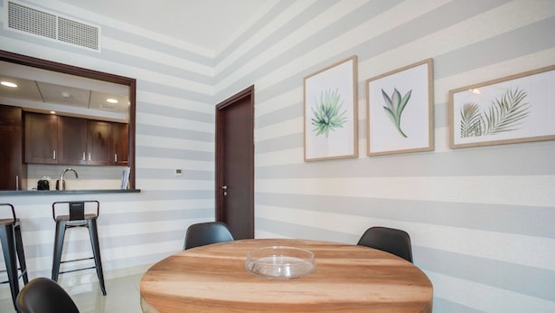 Un coin repas avec une table ronde en bois, des chaises noires et des reproductions botaniques encadrées accrochées au mur.