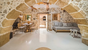 Una habitación con paredes de piedra, un comedor, un sofá y una pequeña mesa.