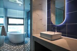 Een moderne badkamer met een vrijstaand bad, een rechthoekig wastafelmeubel en een grote spiegel.