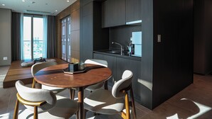 A modern kitchen with dark cabinetry, a built-in oven, and a window overlooking a cityscape. - Hotelaround Sokcho (Sokcho)