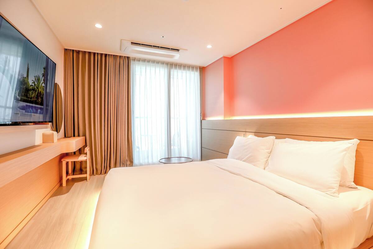 Een moderne hotelkamer met een groot bed, een televisie aan de muur en een bureau met een stoel.