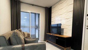 Ein modernes Wohnzimmer mit einem grauen Sofa, einem Holz-TV-Schrank und einer Wand mit Marmoroptik.