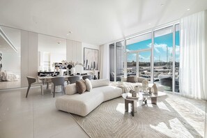 Ein modernes Wohnzimmer mit einer großen Couch, einem Essbereich und Blick auf die Marina.
