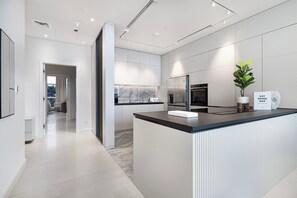 A modern kitchen with a central island, stainless steel appliances, and a view to the living area.