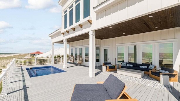 A modern house with a large deck, a swimming pool, and outdoor seating.