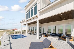 Una casa moderna con una amplia terraza, piscina y mobiliario para exteriores.
