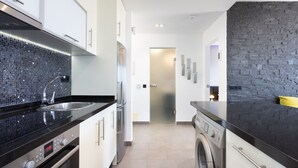 A modern kitchen with a black countertop, stainless steel appliances, and a tiled backsplash. - Attico Boutique Apartment (San Eugenio)