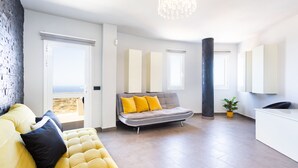 A modern living room with a yellow sofa, a grey sofa with yellow cushions, a white reception desk, and a large window with a view. - Attico Boutique Apartment (San Eugenio)
