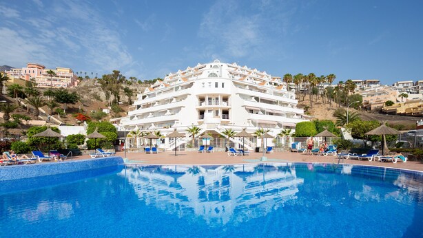 A large hotel with a swimming pool, multiple balconies, and a hillside view. - Attico Boutique Apartment (San Eugenio)