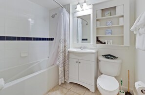 A bathroom with a bathtub, toilet, sink, and shower curtain.