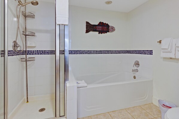 Une salle de bain dotée d’une douche à parois de verre, d’une baignoire et d’un élément décoratif mural représentant des poissons.