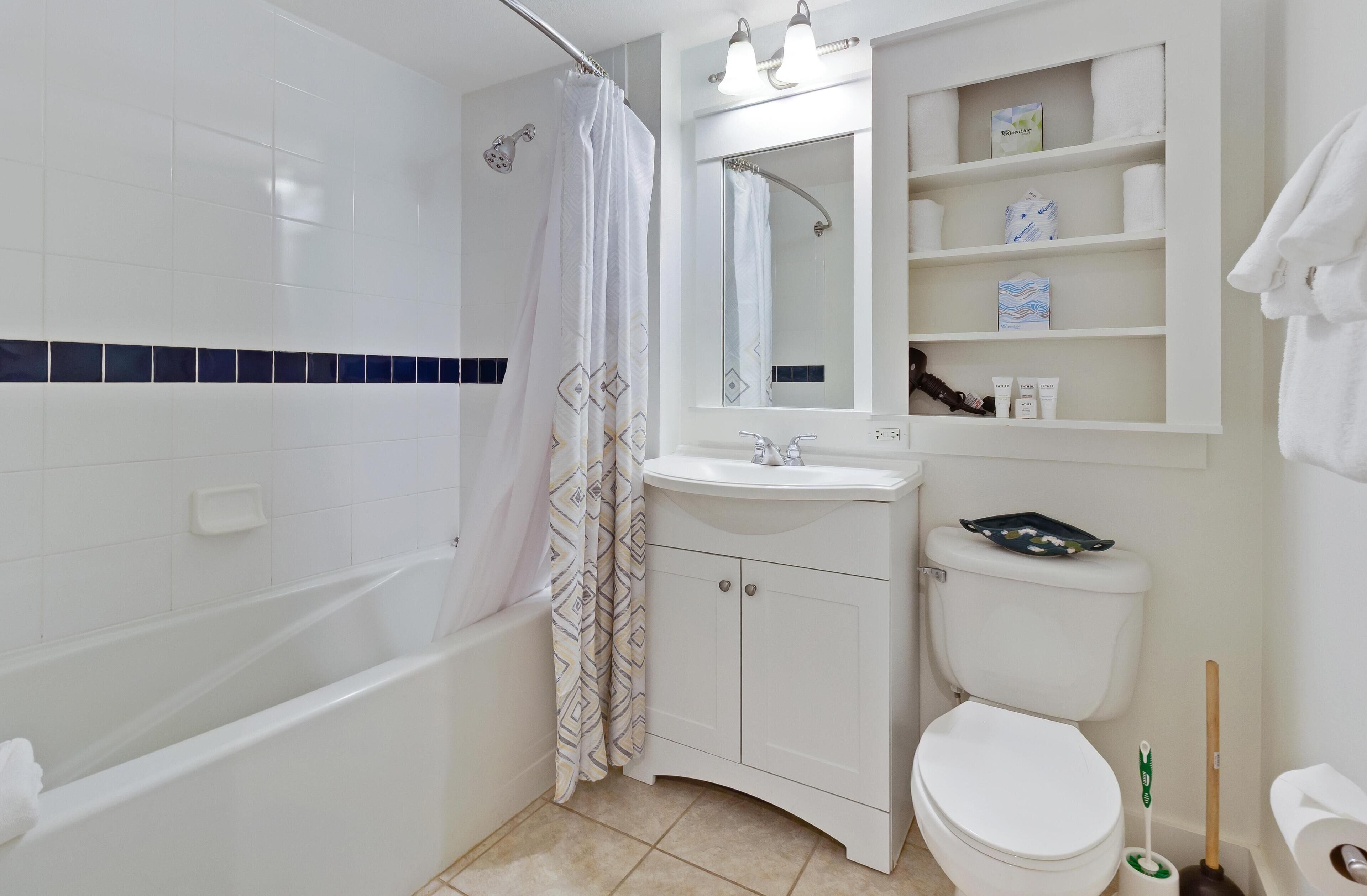 Un baño con bañera, inodoro, lavamanos y cortina de ducha.