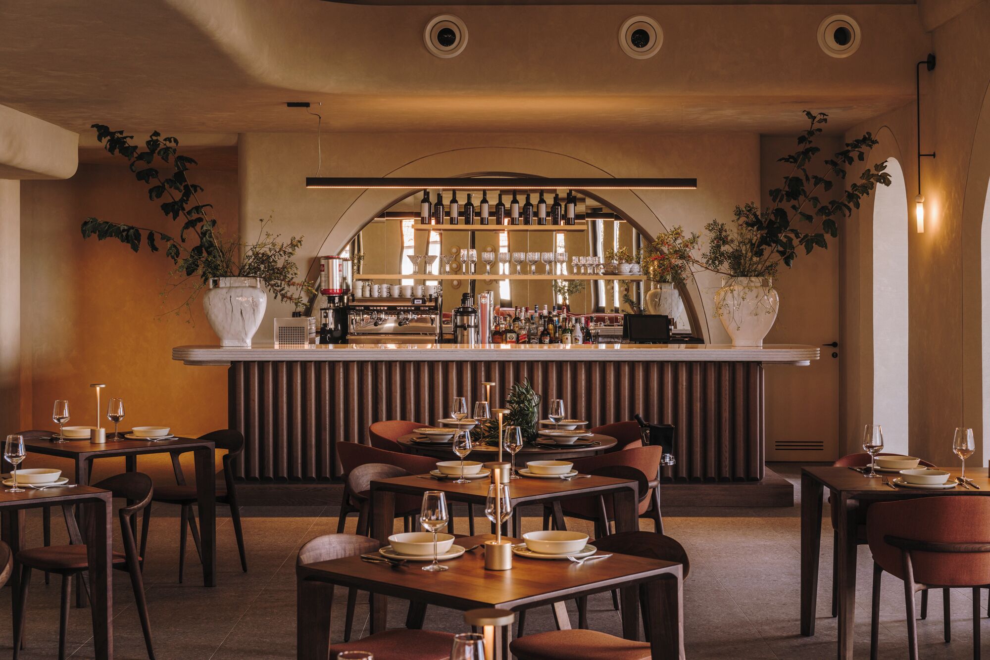 Een restaurant met een bar, meerdere tafels en stoelen.