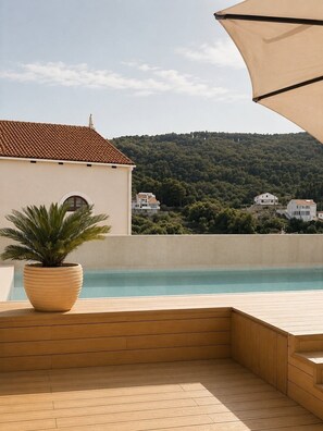 A pool area with a wooden deck, a potted plant, and a view of houses and hills. - Hotel Kali (Kali)