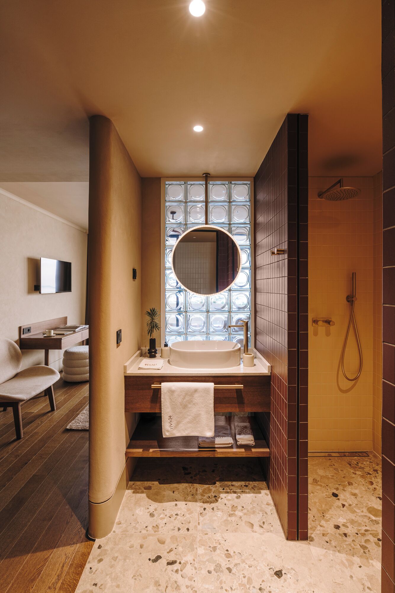 A modern bathroom with a large window, a round mirror, a bathtub, and a shower.