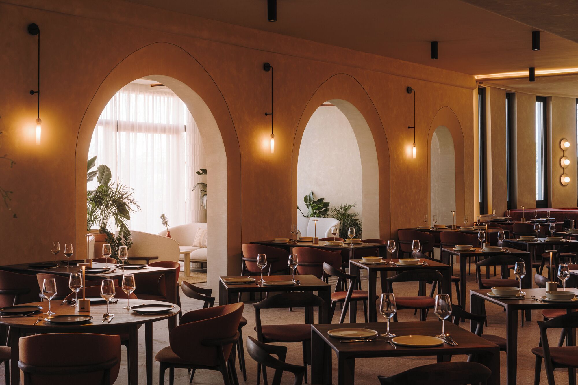 Un ristorante con diversi tavoli e sedie, soffitto a volta e lampade a sospensione.