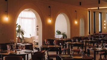 Un ristorante con diversi tavoli e sedie, soffitto a volta e lampade a sospensione.