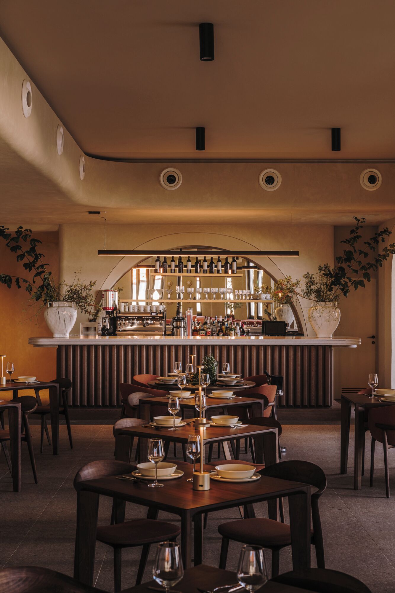 A restaurant with a bar area, multiple tables with chairs, and a warm interior design.