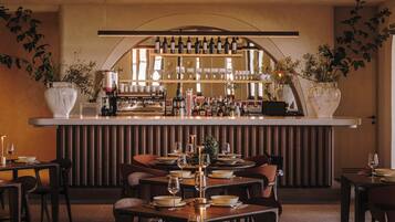 A restaurant with a bar area, multiple tables with chairs, and a warm interior design.