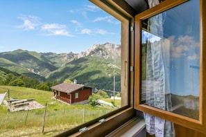 A window with a view of a mountain landscape, a wooden structure, and a fence. - Casa Clelia Centovalli (Centovalli)