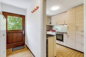 A compact kitchen with wooden cabinets, a built-in oven, and a refrigerator. - Casa Clelia Centovalli With Private Garden (Centovalli)