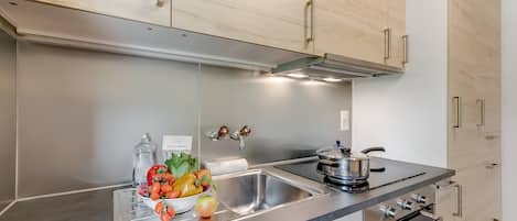 Cozinha moderna com eletrodomésticos de aço inoxidável, bancada de mármore e armários de madeira.