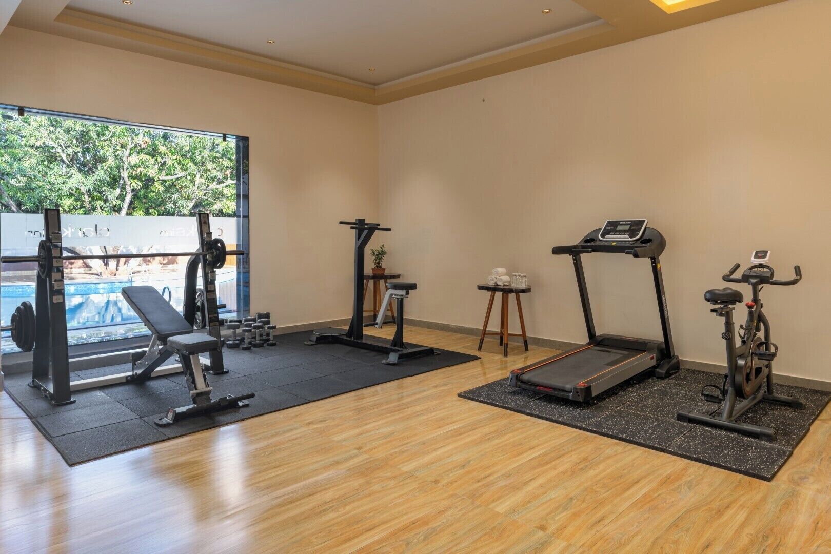 A gym with a treadmill, elliptical, weight bench, and dumbbells.