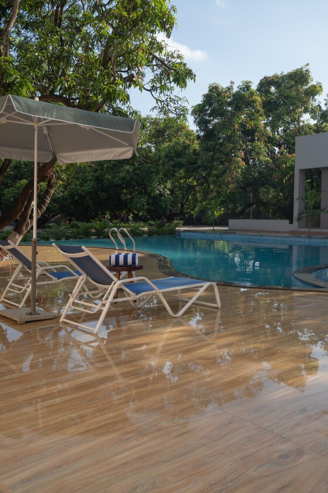 A swimming pool with lounge chairs and an umbrella.