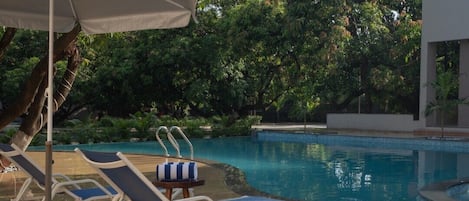 A swimming pool with lounge chairs and an umbrella.