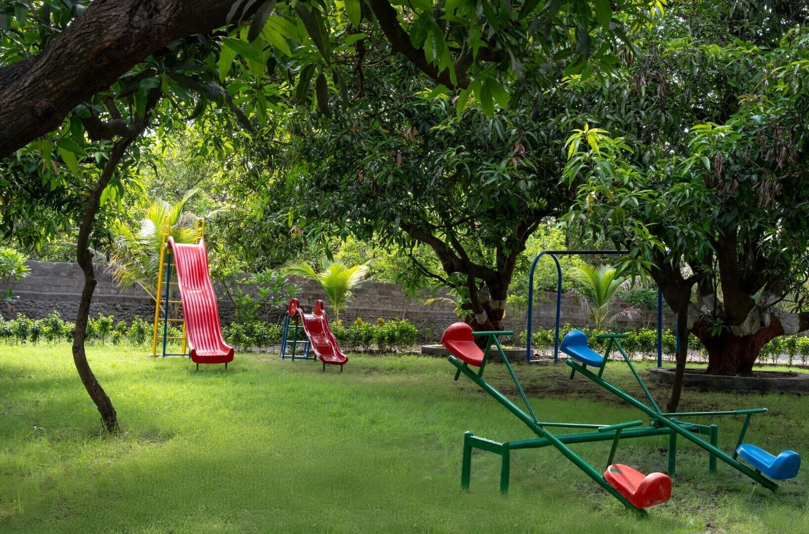 Un patio de juegos con toboganes y columpios rodeado de árboles y césped.