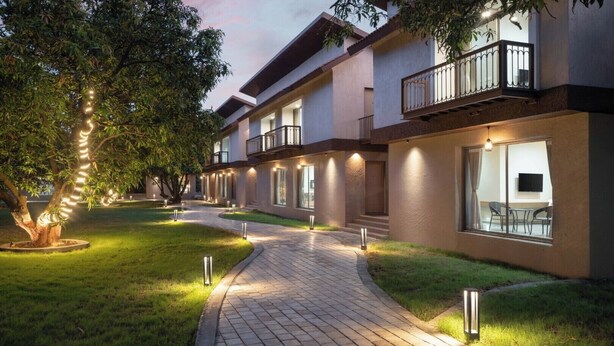 A modern hotel with a paved walkway, large windows, and outdoor seating. - Gir Aatithya Clarks Inn  (Talala)