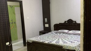A bedroom with a bed, a nightstand, and a wall-mounted heater. - Modern Apartment with Kitchen & Wi-Fi – Perfect for Work & Relaxation (Sahibzada Ajit Singh Nagar)