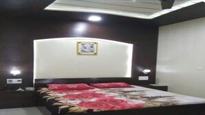 A bedroom with a bed, dark wooden headboard, two bedside lamps, and a framed picture on the wall. - Modern Apartment with Kitchen & Wi-Fi – Perfect for Work & Relaxation (Sahibzada Ajit Singh Nagar)
