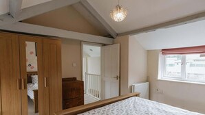 A bedroom with a bed, wooden wardrobe, and a window with a view. - Elm House Cottage: Charming Country Cottage with Log Burner (High Hesket)