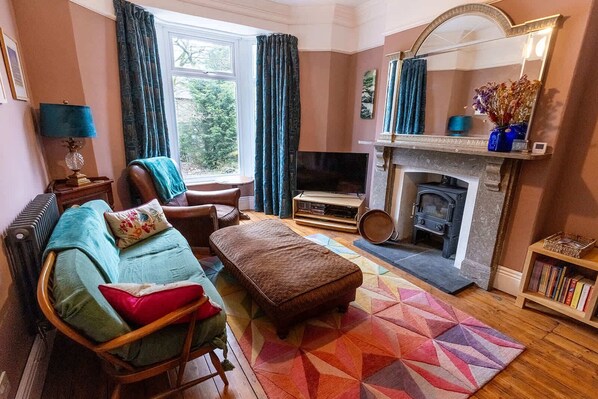 Una sala de estar acogedora con sofá, sillón y reposapiés, chimenea y televisor.