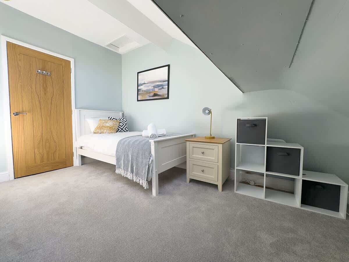 A bedroom with a bed, a desk, a chair, and built-in shelving.