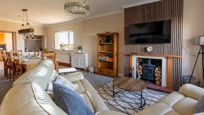 Una sala de estar con sofá, mesa de centro, chimenea, televisión y estantería.