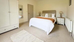 Quarto com cama, mesas de cabeceira, guarda-roupa e radiador.