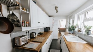 A kitchen with white cabinets, wooden countertops, a toaster, a kettle, and a sink. - Charming Ulverston Cottage with Garden & Views (Westmorland and Furness)