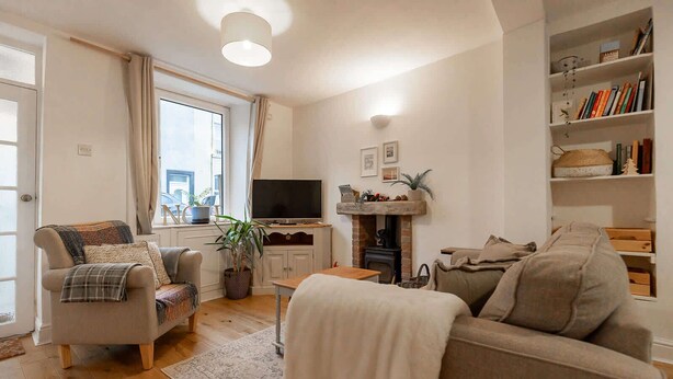 A cozy living room with a fireplace, a television, and a bookshelf. - Charming Ulverston Cottage with Garden & Views (Westmorland and Furness)