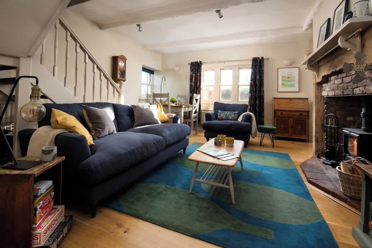 A cozy living room with a blue sofa, a wooden coffee table, and a fireplace.