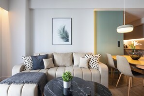 A modern living room with a sofa, a coffee table with a plant, and a dining area with chairs and a table. - Nostalgia 1-Bedroom Apartment in Athens (Athens)
