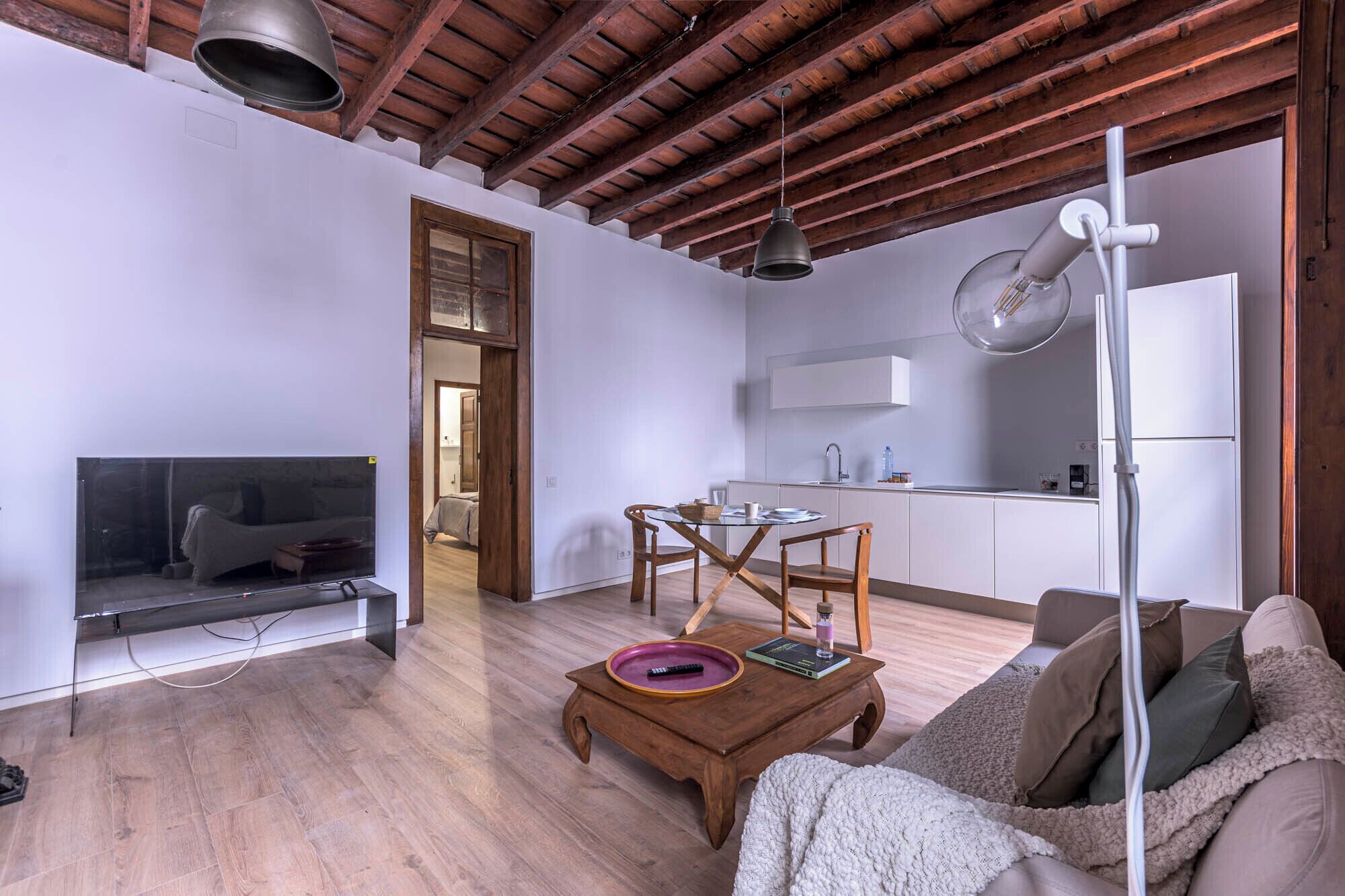 A living room with a wooden ceiling, a TV, a coffee table, and a sofa.