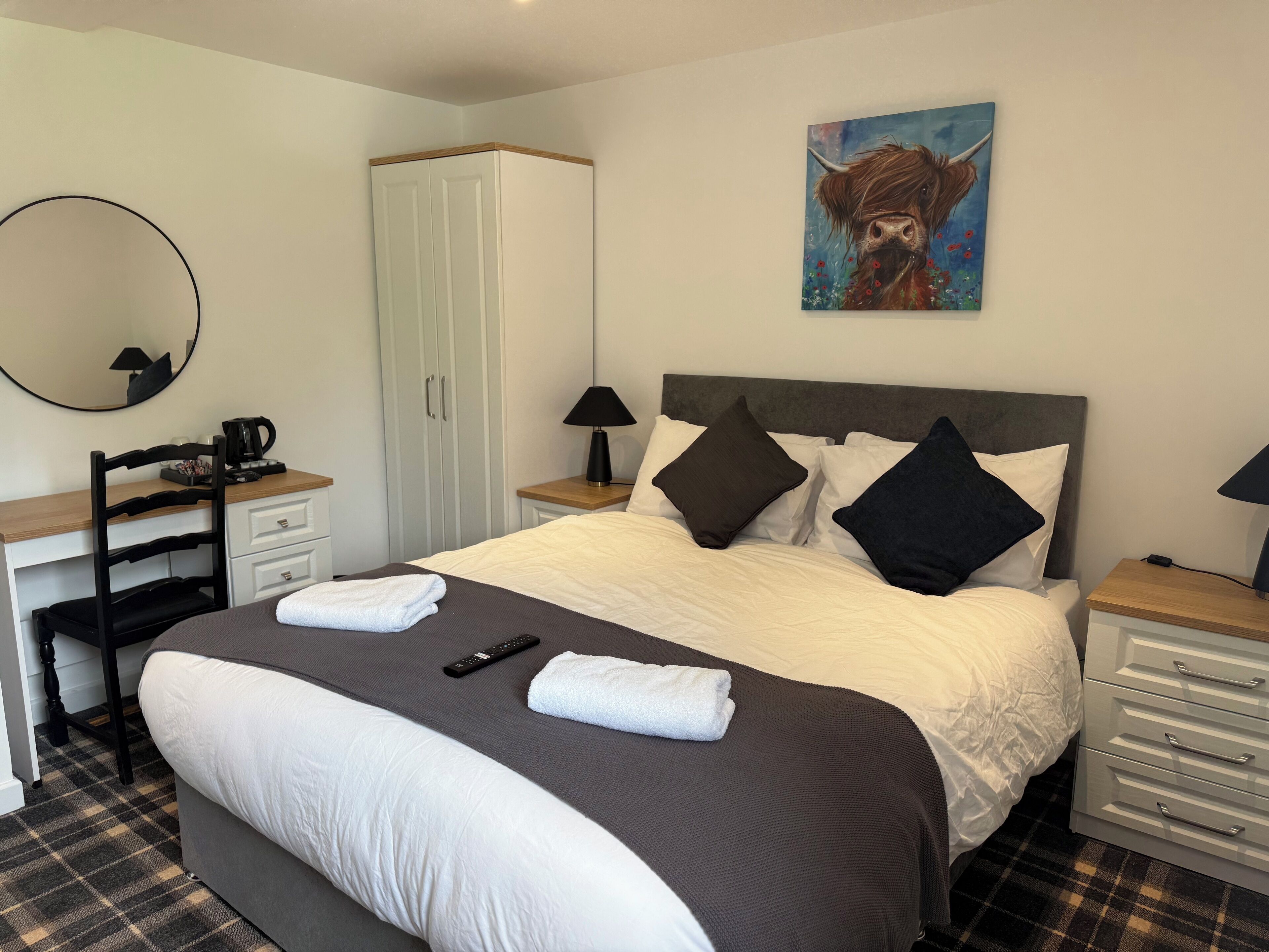 A neatly arranged bedroom with a bed, bedside tables, a desk, and a wardrobe.