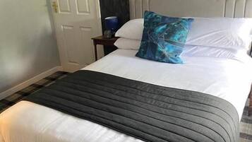 Une chambre d’hôtel avec un lit, une table de chevet, une porte et un tableau accroché au mur.