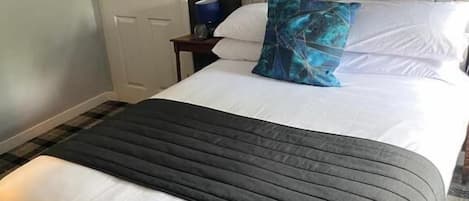 Una camera d'albergo con un letto, un comodino, una porta e un quadro appeso al muro.