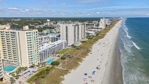 A coastal hotel with multiple high-rise buildings, a beach, and a swimming pool.